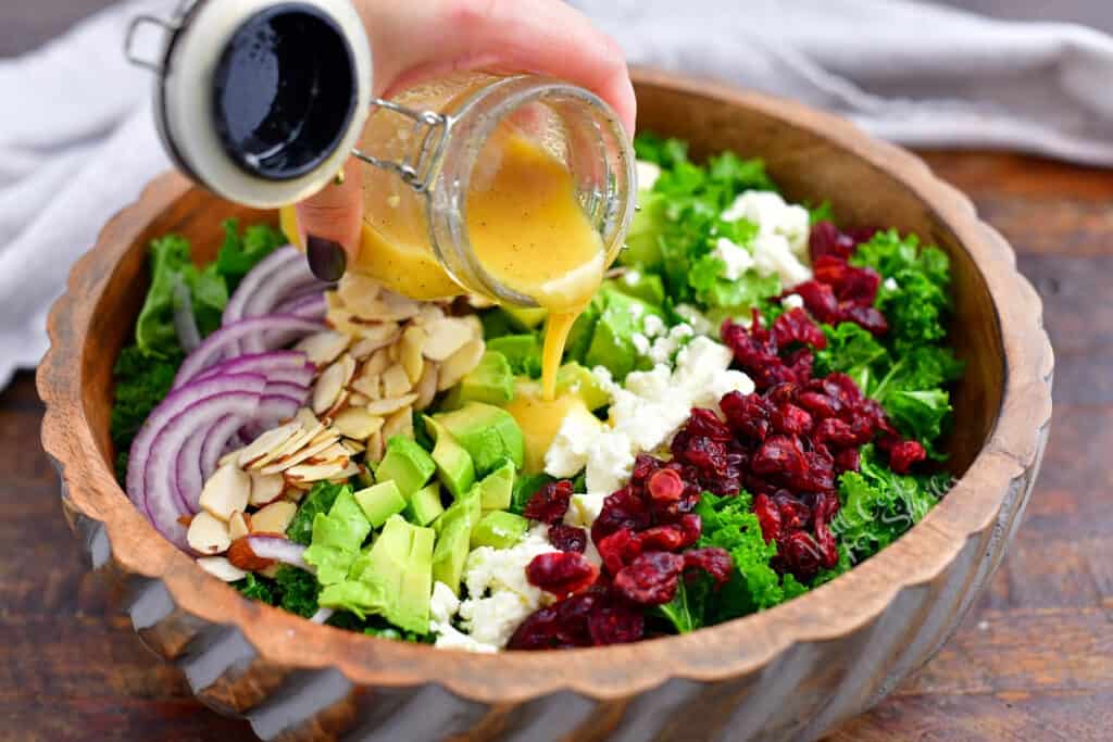 pouring salad dressing over healthy vegetables salad