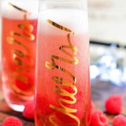 fresh raspberries scattered around two Kir Royale cocktails