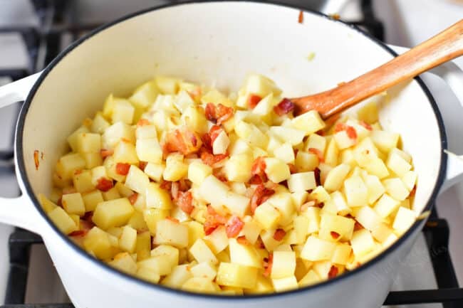 making a potato soup recipe- stirring potatoes and bacon a white pot