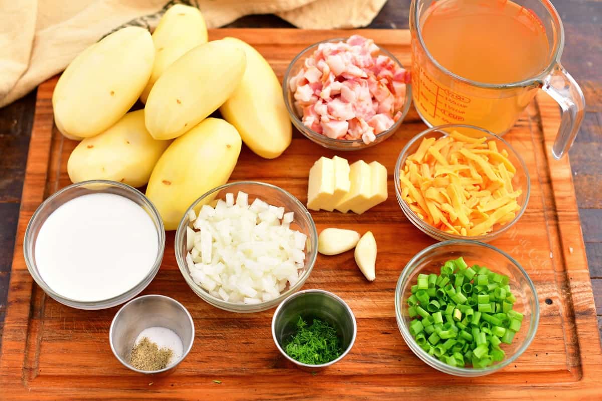 fresh ingredients for a loaded potato soup recipe laid out on a wooden cutting board.