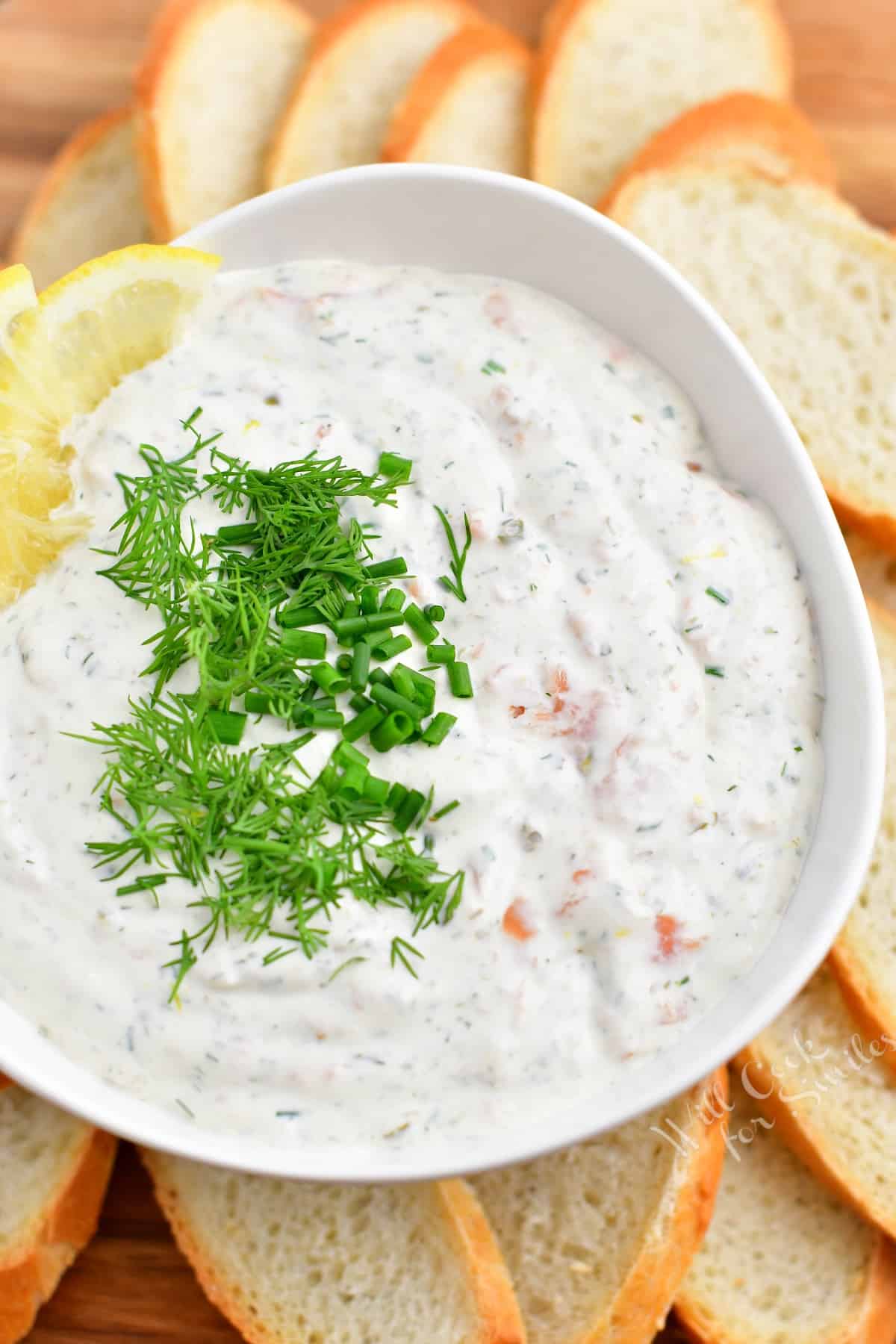 overhead image: white bowl filled with creamy white dip garnished with dill and lemon slice