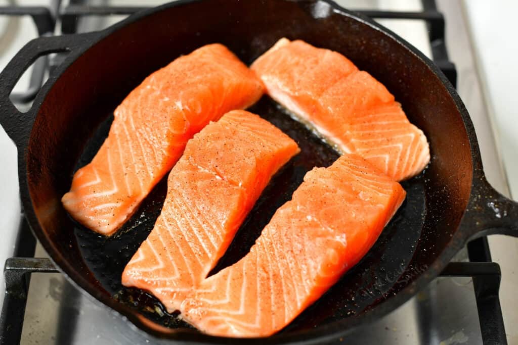 pan searing salmon fillets in a cast iron skillet