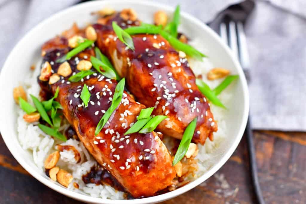 closeup: teriyaki salmon topped with scallions and sesame seeds on a bed of rice