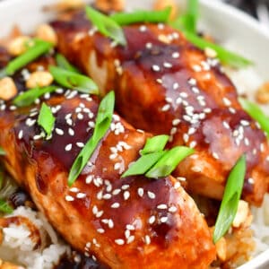 closeup: teriyaki baked salmon topped with scallions and sesame seeds on a bed of fluffy rice