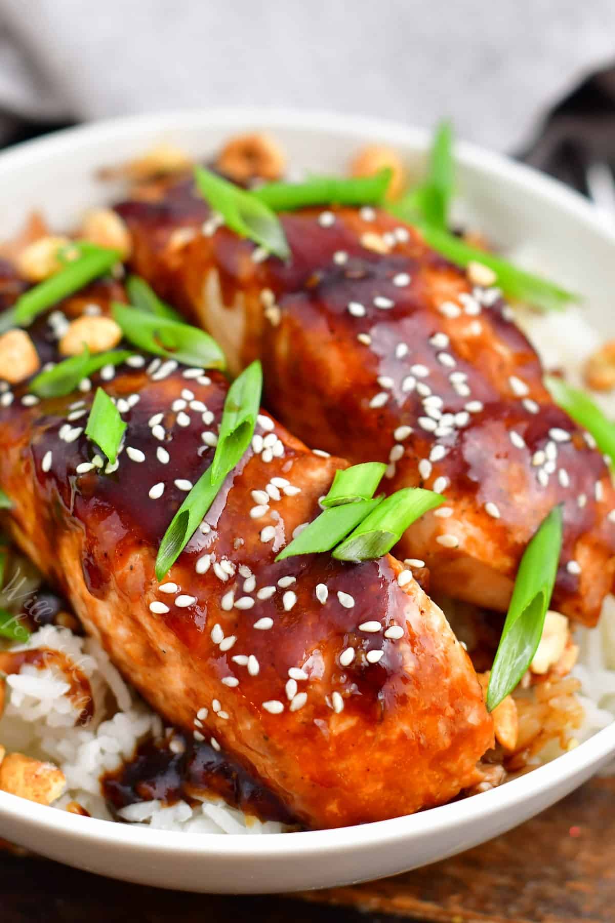 closeup: teriyaki baked salmon topped with scallions and sesame seeds on a bed of fluffy rice