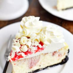 slice of white chocolate raspberry cheesecake on a white plate with a fork