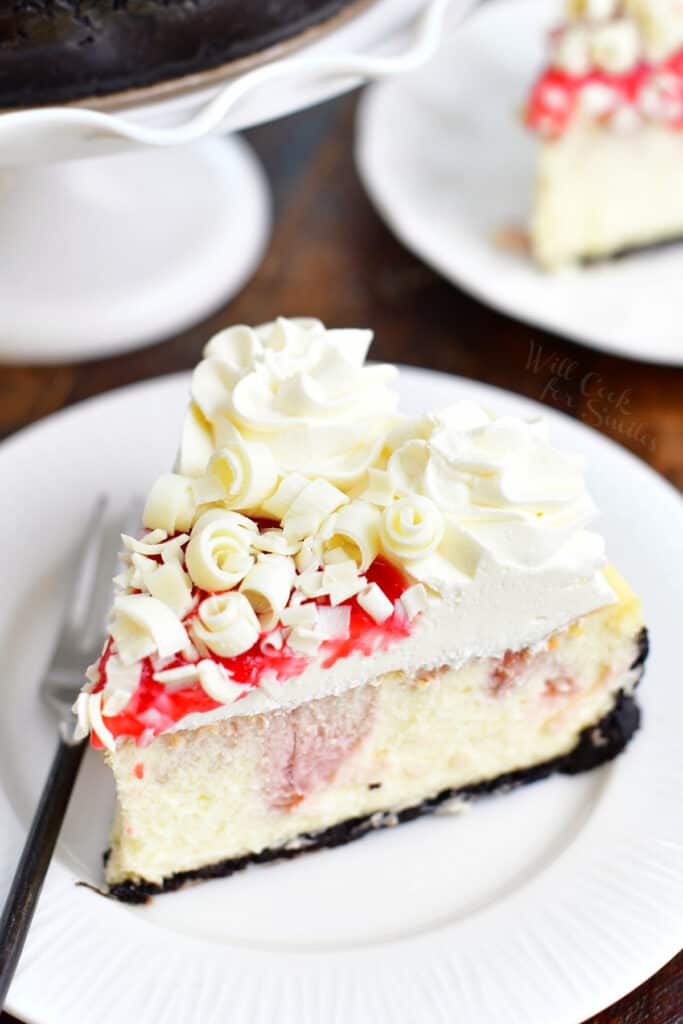 slice of white chocolate raspberry cheesecake on a white plate with a fork