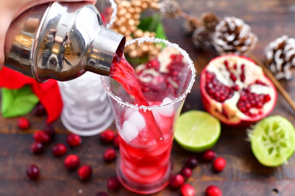 pouring the red cocktail into glass with ice and salt rim