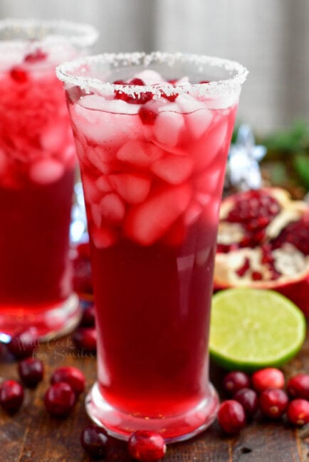 tall glass with margarita cocktail and pomegranate lime and cranberries around