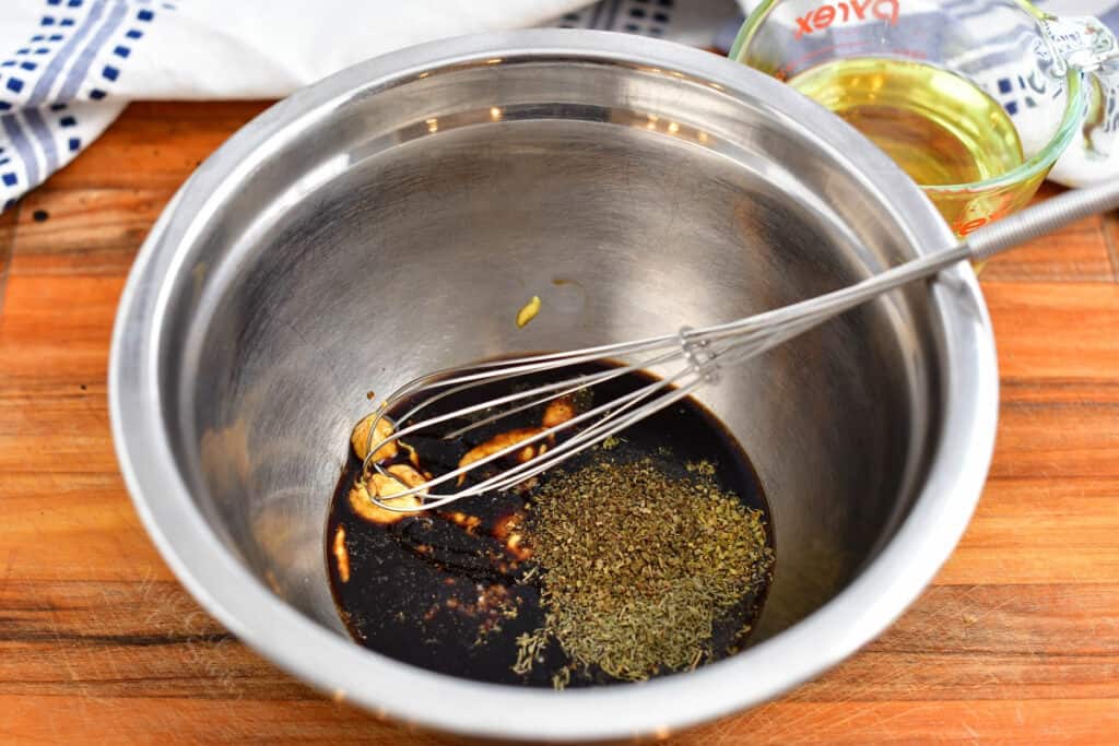 salad dressing recipe ingredients being whisked in a metal bowl