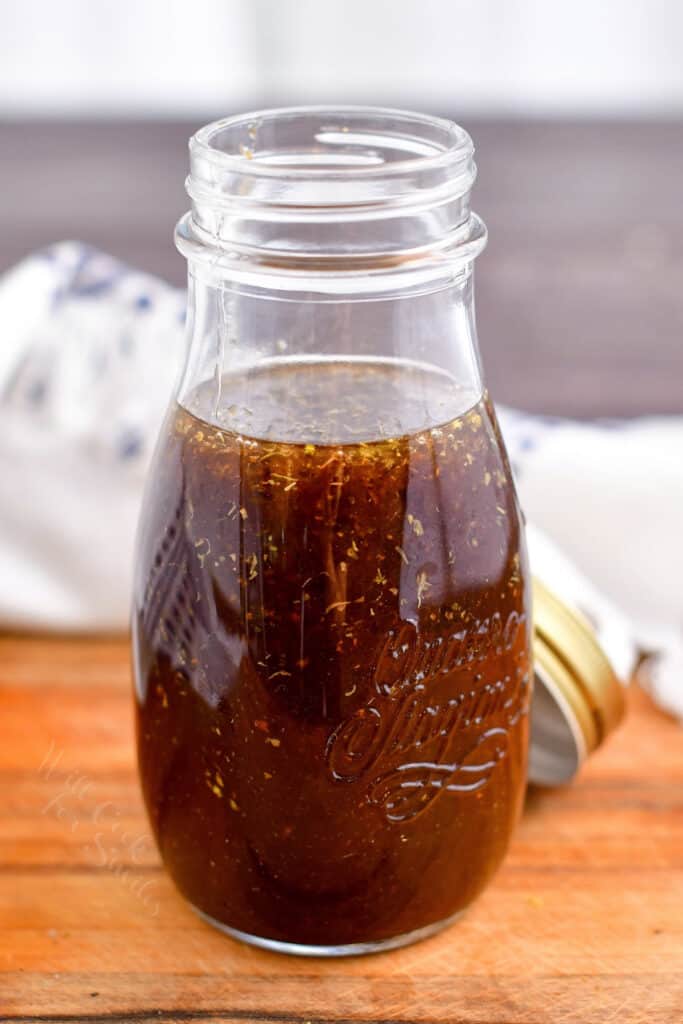 open glass jar of balsamic dressing on a wooden surface