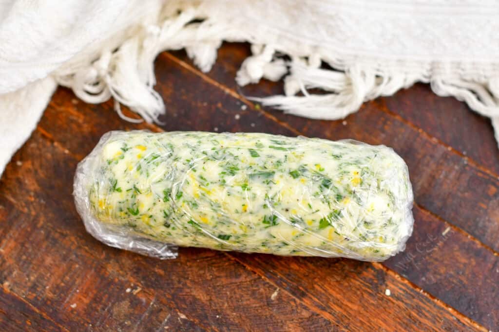 compound herb butter rolled in plastic wrap on counter