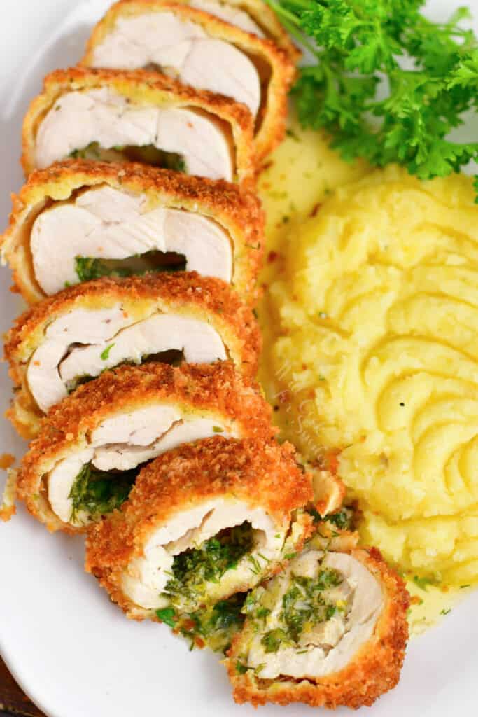 slices of chicken kiev fanned out on plate with whipped potatoes and fresh parsley