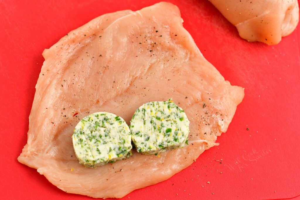 2 pieces of compound butter on top of raw chicken breast cutlet