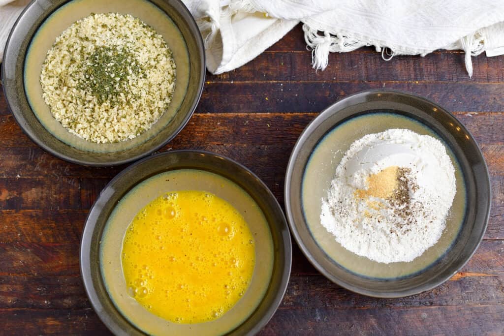 bowls of seasoned flour, whisked egg yolks and seasoned panko bread crumbs