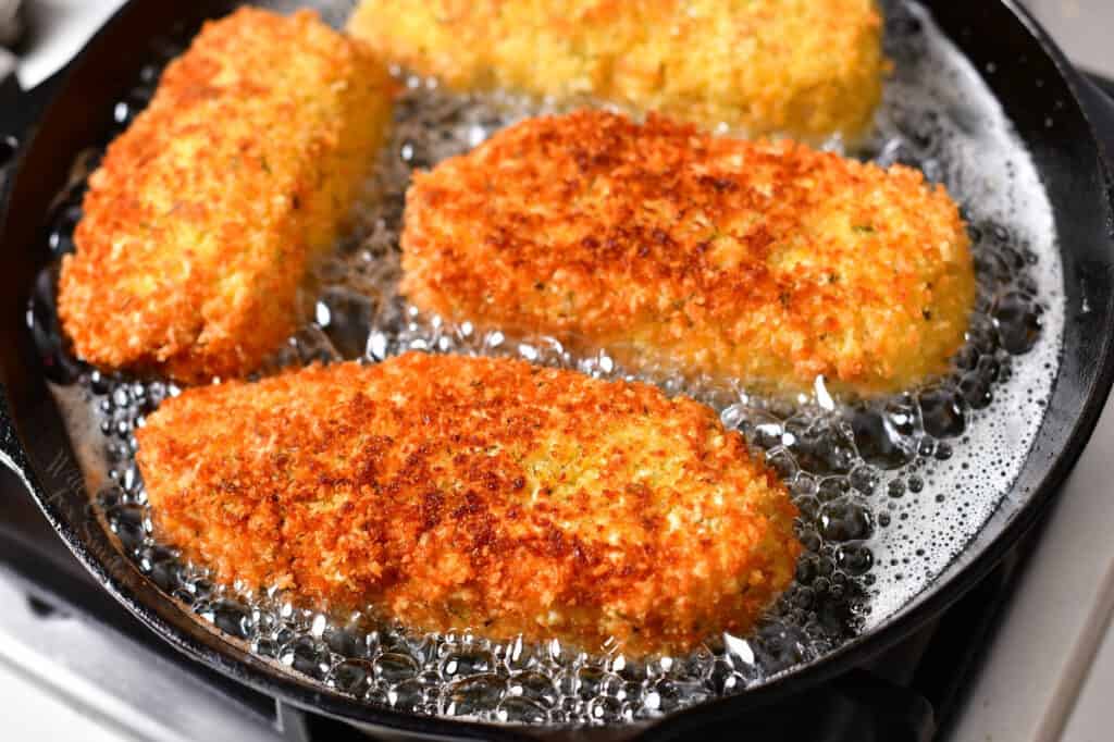 crispy golden chicken kiev cooking in skillet