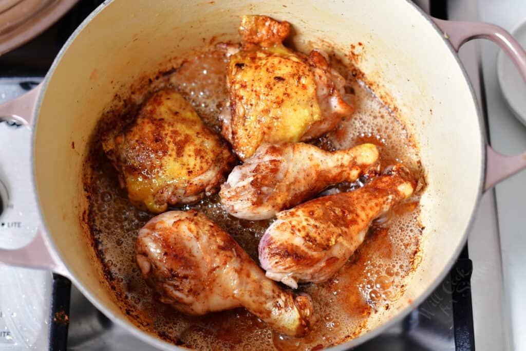 dutch oven with chicken thighs and drumsticks browning in bacon grease