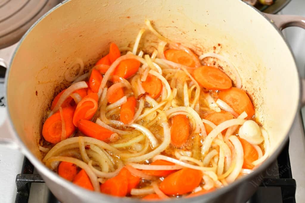 sliced onions and carrots cooking in bacon fat