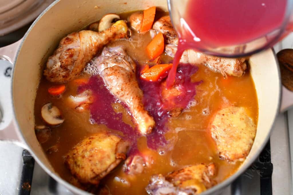 tomato and wine picture being poured into pot of chicken, vegetables, and cognac