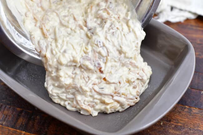 French onion dip being poured into a greased baking dish