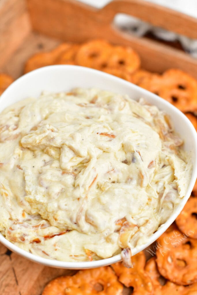 bowl of white dip surrounded by pretzel chips