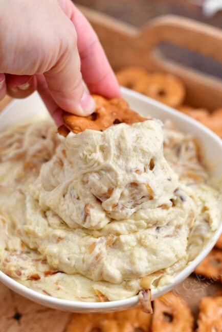pretzel chip being dipped into a bowl of French onion dip