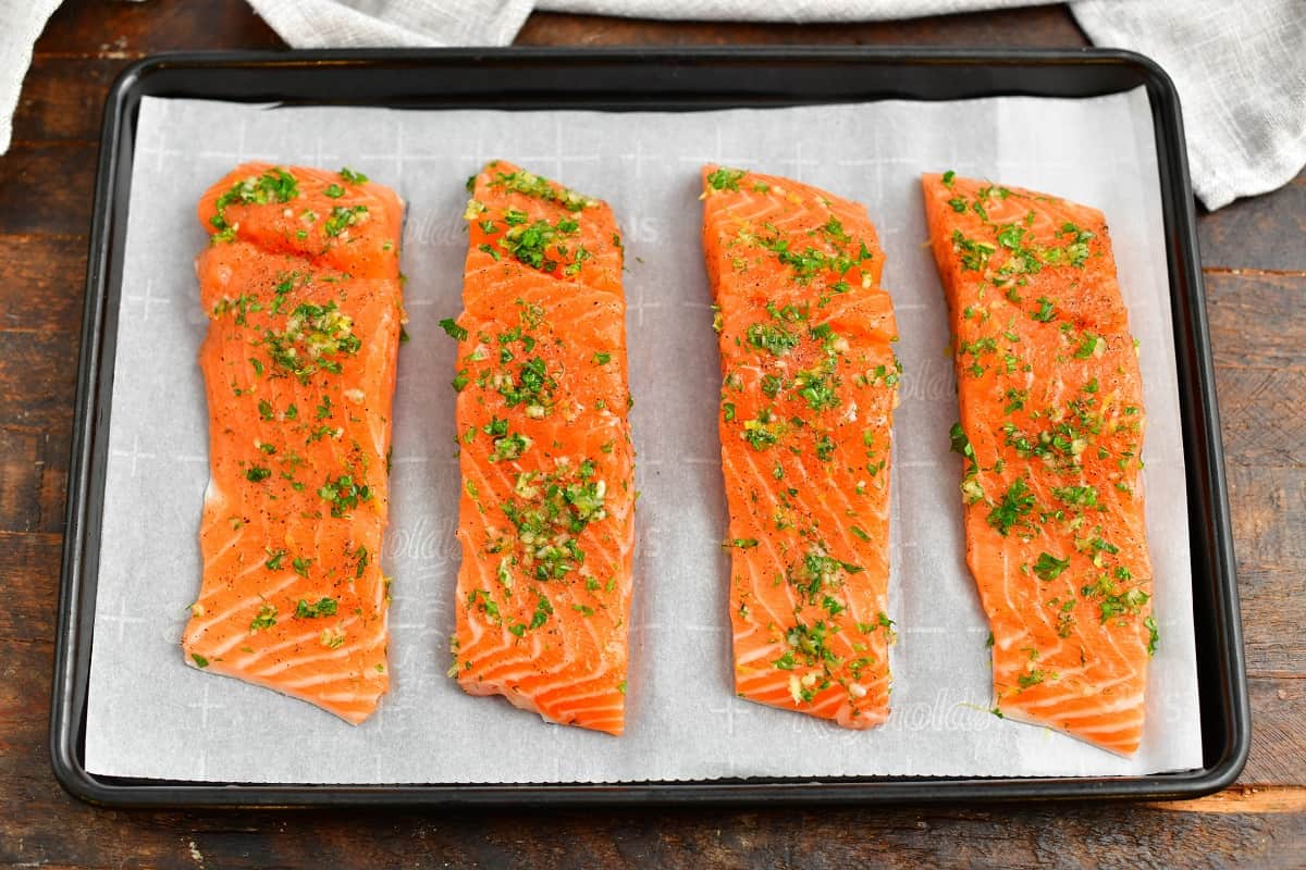 four pieces of raw fish on parchment lined baking sheet