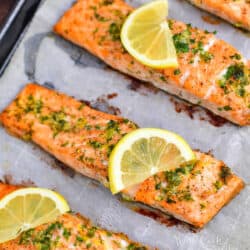 healthy baked salmon on baking sheet topped with slices of lemon