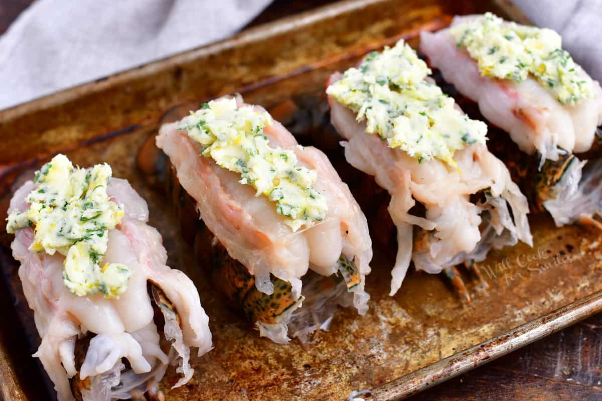 4 raw lobster tails topped with compound butter, ready for baking