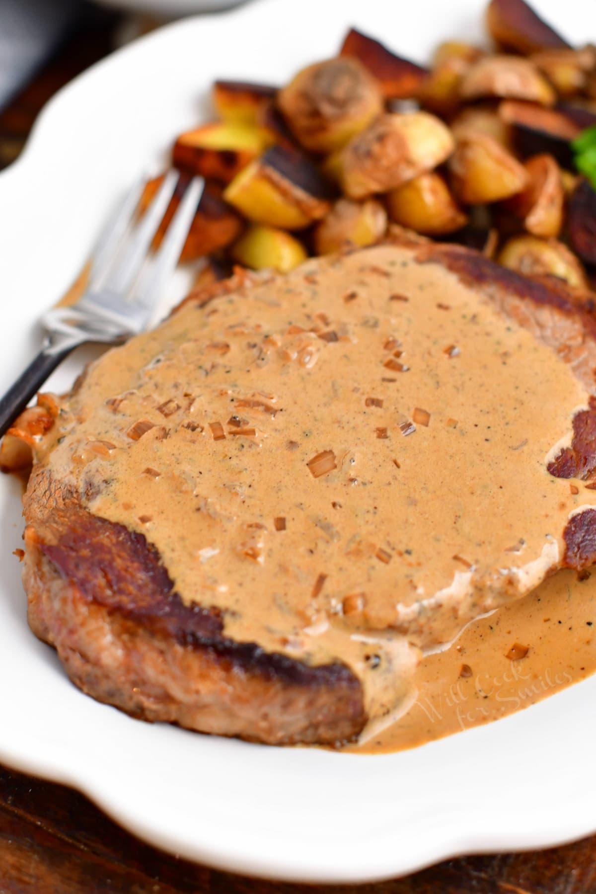 ribeye smothered in peppercorn sauce with roasted potatoes