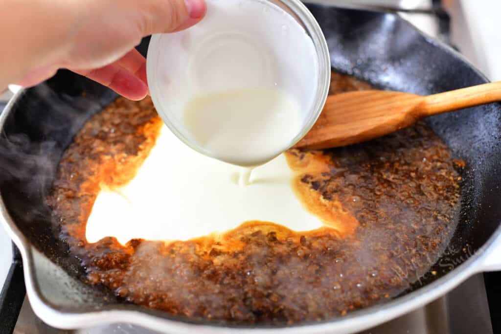 pouring heavy cream into brown sauce