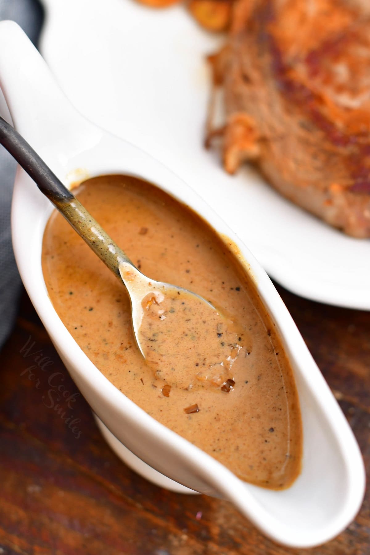creamy brown sauce in white gravy boat with spoon