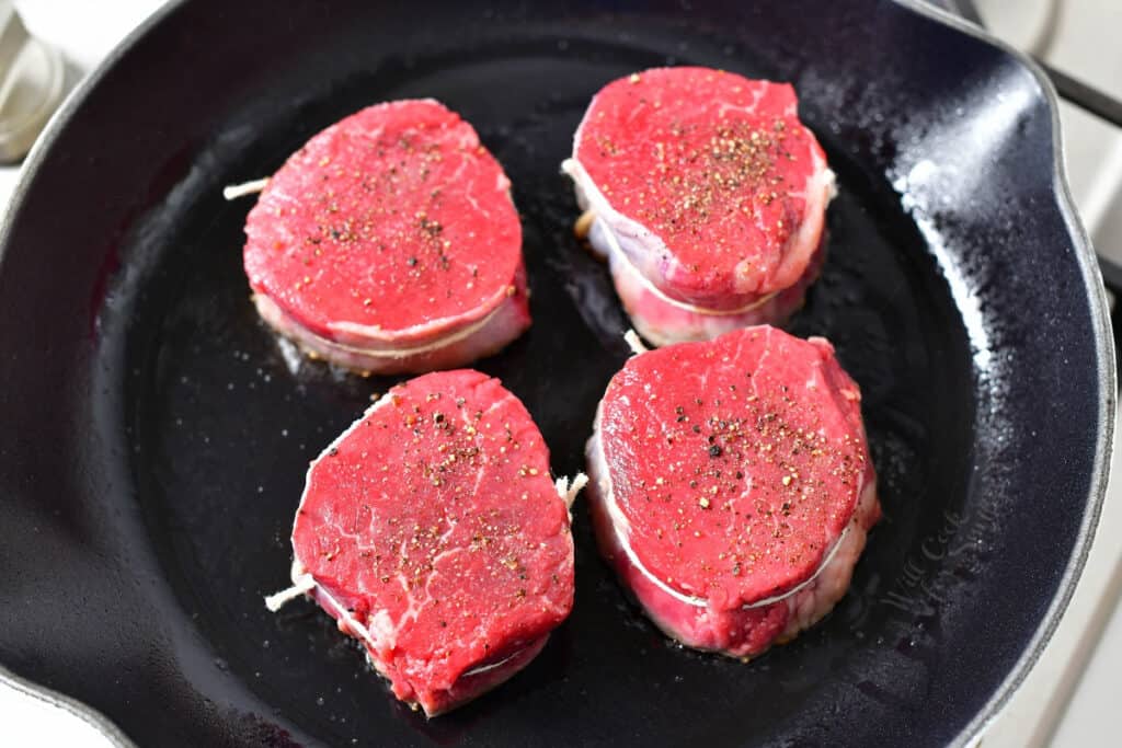 4 raw filet mignon steaks in a skillet