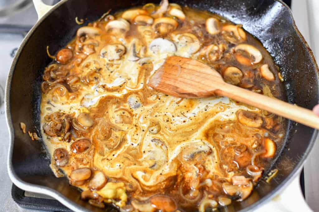stirring cream into steak diane sauce with mushrooms and shallots