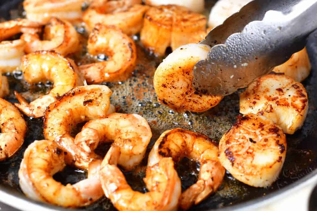 close up photo of shrimp and scallops being seared in a pan