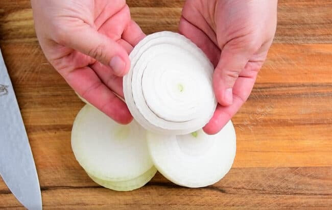 woman's hands holding slice of onion and separating rings out
