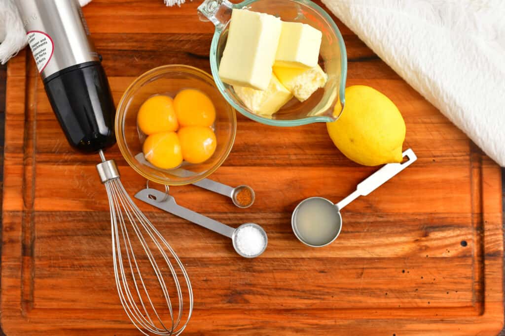 The ingredients for Eggs Benedict are placed on a wooden surface.