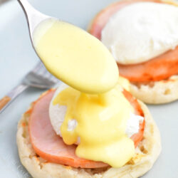 Hollandaise sauce is being drizzled on top of Eggs Benedict.