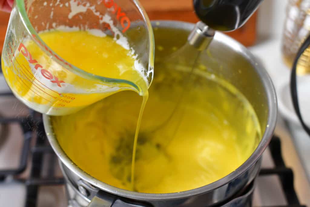 Ingredients for hollandaise sauce are being combined in a large pot.