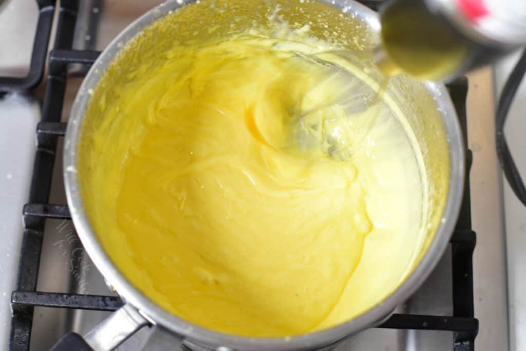 The hollandaise sauce is being whisked in a pot.