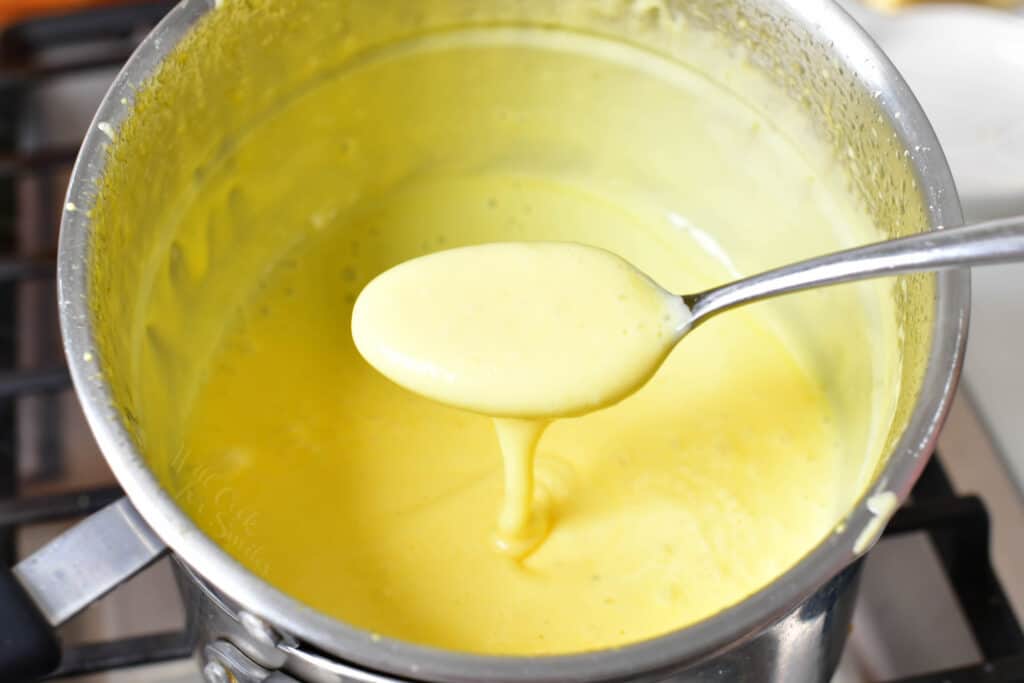 A spoon is holding a small portion of sauce over the pot.