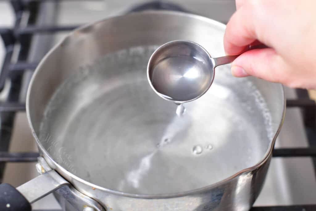 White vinegar is being added to a pot of water.
