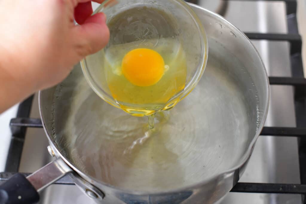A raw egg is being added to the boiling water.