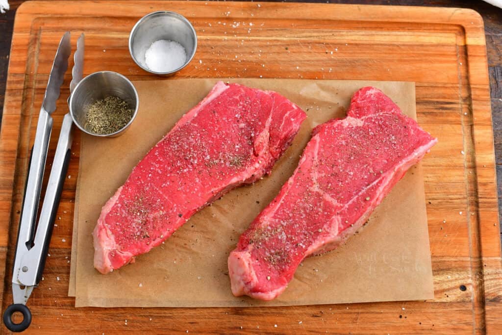 uncooked steaks seasoned with salt and pepper
