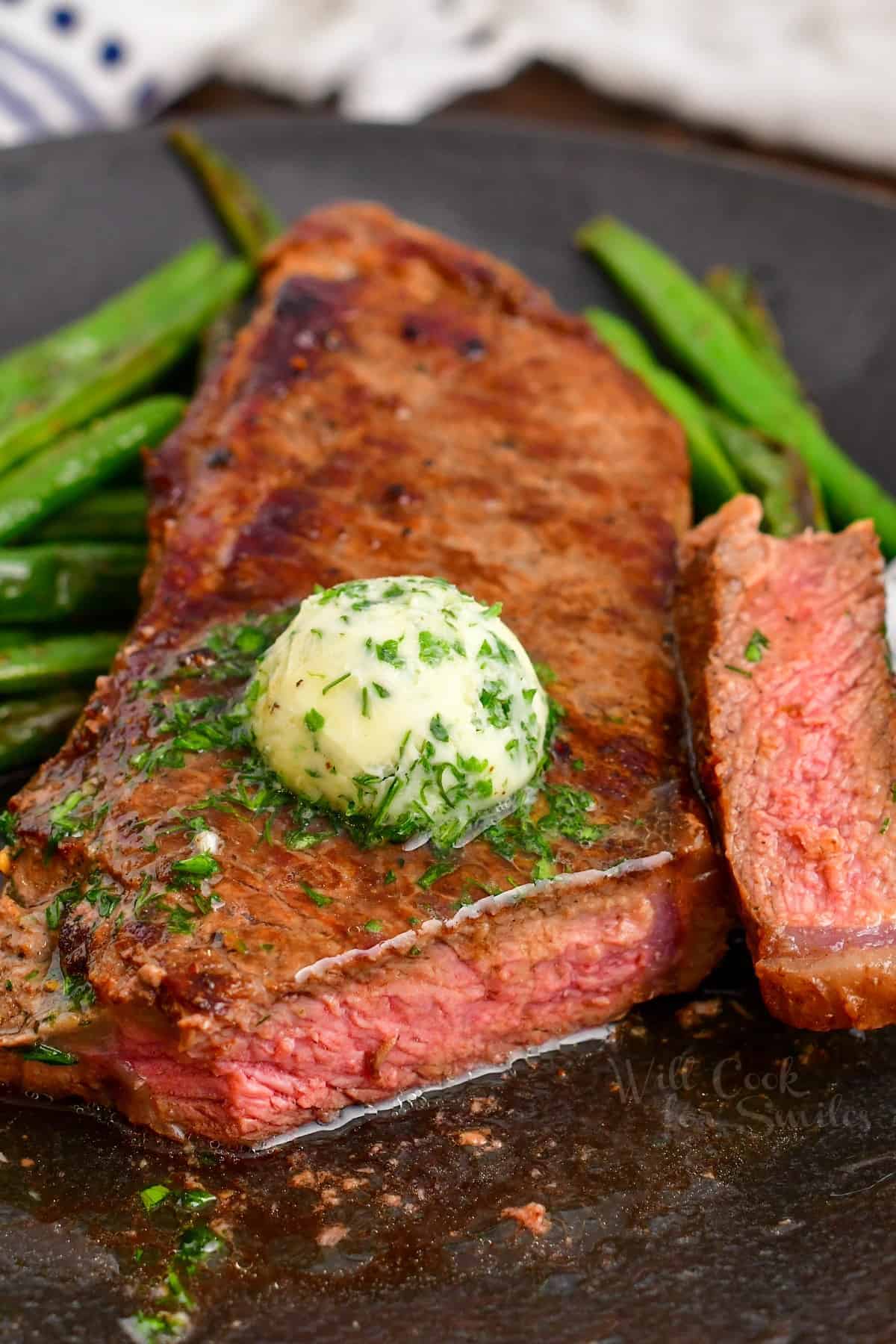 cast iron steak with the end sliced off surrounded by green beans