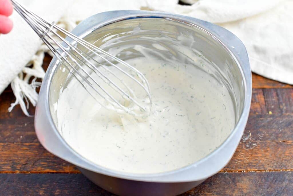 whisking buttermilk ranch dressing in a metal bowl