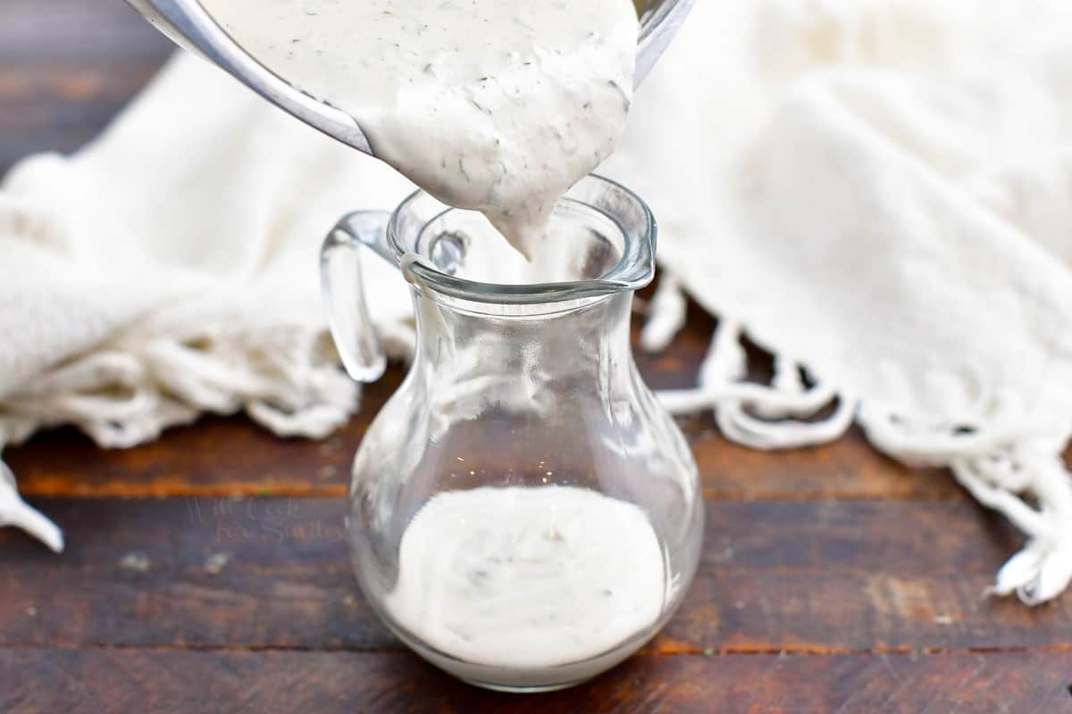 pouring homemade ranch dressing into a small glass pitcher