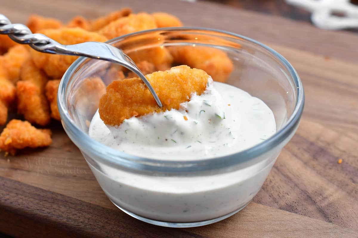 dipping breaded chicken pieces in a bowl of homemade ranch dressing