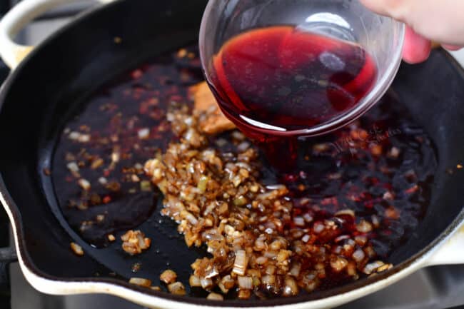 stir in red wine into pan with sauteed shallots, garlic, and cognac