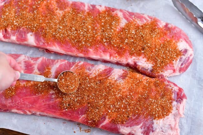 applying dry rub for pork onto rack of ribs before baking